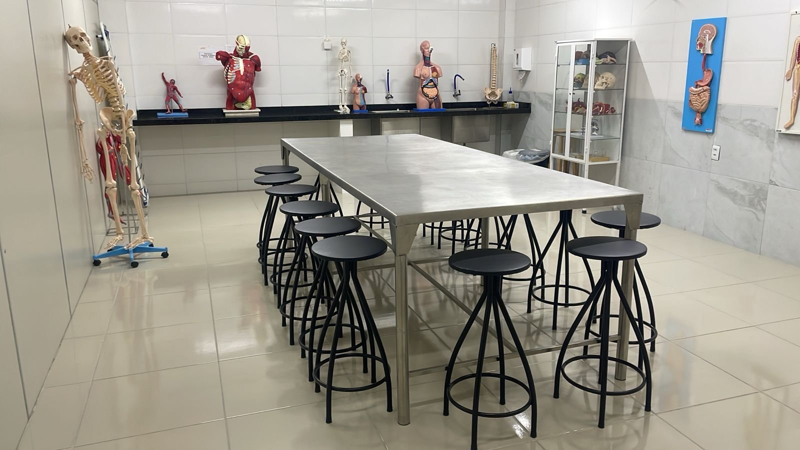 Laboratório com modelos anatômicos, bancada e assentos